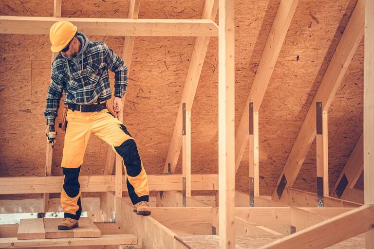 Homeowners review renovation plans, material samples, and a handwritten budget at a kitchen table.